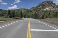 an empty empty road in the country side and mountains in the background in the summer