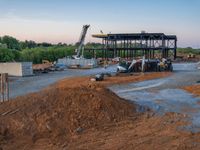 a picture of a building being built on a field near a forest in the background