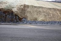 a rock wall at the end of the road is shown being constructed using a gravel pile and a stone foundation