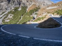 a curve in the middle of a road near a mountain range with low lying grass