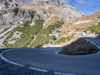 a curve in the middle of a road near a mountain range with low lying grass