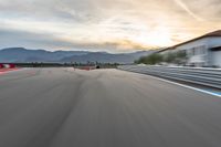 a photo of a dirt race track with sun setting in the distance of the track