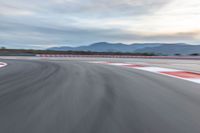 a photo of a dirt race track with sun setting in the distance of the track