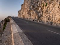 a road leading into a cliff with the ocean in the back ground and a building in the corner