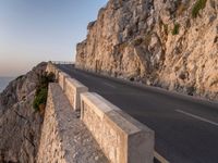 a road leading into a cliff with the ocean in the back ground and a building in the corner