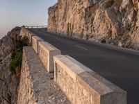 a road leading into a cliff with the ocean in the back ground and a building in the corner