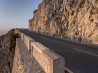 a road leading into a cliff with the ocean in the back ground and a building in the corner