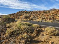 a road winding through a desert landscape under a clear blue sky on the mountain, there are no clouds