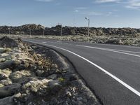 a paved road in the middle of nowhere with rocks on both sides of the road