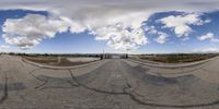 a fish eye lens view of an empty road with the sky above and a mountain in the distance