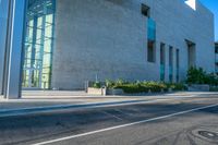 the side of an empty city street next to a building with a large glass wall