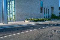 the side of an empty city street next to a building with a large glass wall