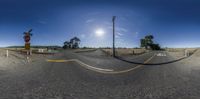 360 - view of road with fence, sign and pole for a stoplight in the middle of nowhere