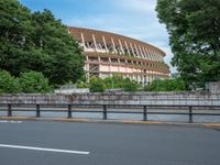 a view of a stadium from the street, showing many trees and bushes in the distance