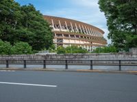 a view of a stadium from the street, showing many trees and bushes in the distance