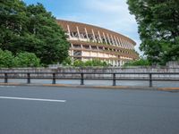 a view of a stadium from the street, showing many trees and bushes in the distance