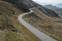 a motorcycle parked on a small mountain side road near mountains with no cars driving on it