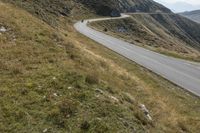 a motorcycle parked on a small mountain side road near mountains with no cars driving on it