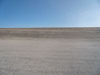 a person on a motorcycle standing on top of a road in the middle of nowhere