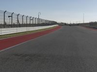 an empty track at a motorsports club with some red and white stripeing on it