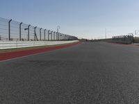 an empty track at a motorsports club with some red and white stripeing on it