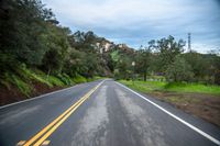 a long road that has a hill behind it and houses on the side of it