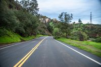 a long road that has a hill behind it and houses on the side of it