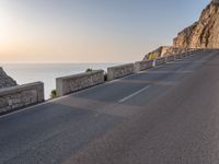 a large long empty road next to a cliff side on the ocean's edge