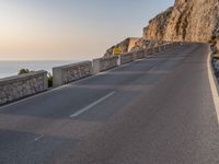 a large long empty road next to a cliff side on the ocean's edge