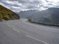 a car is parked on the road in the mountains area of europe with mountains in the background