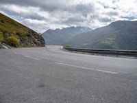 a car is parked on the road in the mountains area of europe with mountains in the background