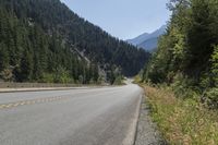 the motorcycle is parked on the side of the road with trees and mountain in the background