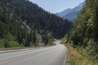 the motorcycle is parked on the side of the road with trees and mountain in the background