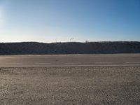 a dirt field that has a hill and sky in the background with rocks and a white line