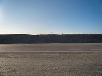 a dirt field that has a hill and sky in the background with rocks and a white line