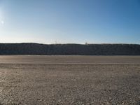 a dirt field that has a hill and sky in the background with rocks and a white line