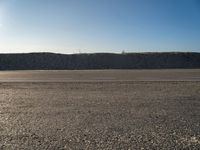 a dirt field that has a hill and sky in the background with rocks and a white line