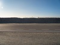 a dirt field that has a hill and sky in the background with rocks and a white line