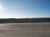 a dirt field that has a hill and sky in the background with rocks and a white line