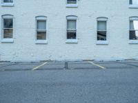 a street with a building near the building in the middle and on the left of which is a parking lot, as shown in this photo