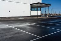 a car parked on the side of a parking lot in front of a building with white lines painted in