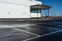 a car parked on the side of a parking lot in front of a building with white lines painted in