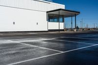 a car parked on the side of a parking lot in front of a building with white lines painted in