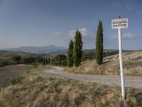 a road sign on a small hill side in the country side area of italy, with an empty road