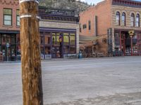 a red fire hydrant sitting in front of an old store window and building next to an open air field