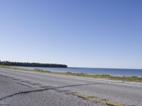 the road stretches out towards a blue body of water on an island on which an upside down sign is leaning on