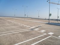 an empty parking lot is shown with some street lights in the foreground and signs to indicate where to go