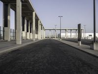 a wide open empty parking space in an industrial setting with a sky background and columns