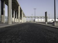 a wide open empty parking space in an industrial setting with a sky background and columns