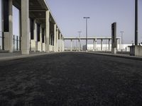 a wide open empty parking space in an industrial setting with a sky background and columns